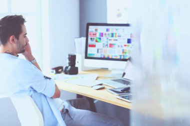 İnternette çalışırken bilgisayarın ve dizüstü bilgisayarın önünde grafik stüdyosunda oturan genç tasarımcının portresi.