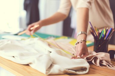 Stüdyoda tasarımcı kadın tasarımları üzerinde çalışıyor.