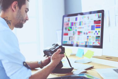 İnternette çalışırken bilgisayarın ve dizüstü bilgisayarın önünde grafik stüdyosunda oturan genç tasarımcının portresi.