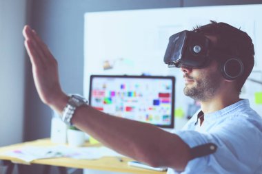 Genç erkek yazılım programcısı ofiste üç boyutlu sanal gerçeklik gözlükleriyle yeni bir uygulama test ediyor..