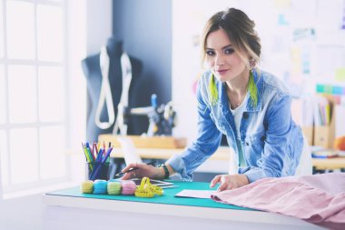 Stüdyoda tasarımcı kadın tasarımları üzerinde çalışıyor.