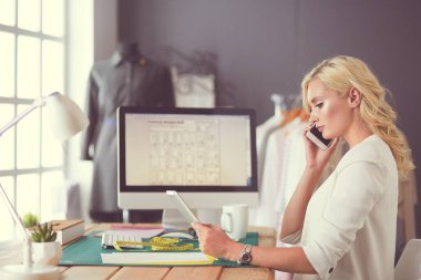 Stüdyoda tasarımcı kadın tasarımları üzerinde çalışıyor.