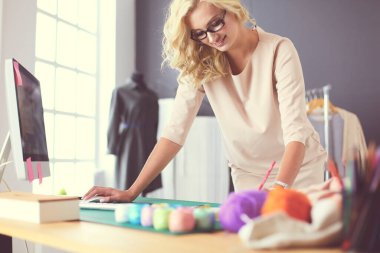 Stüdyoda tasarımcı kadın tasarımları üzerinde çalışıyor.