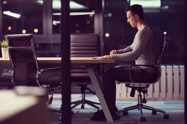 暗いオフィスでノート パソコンで作業する人 — ストック写真