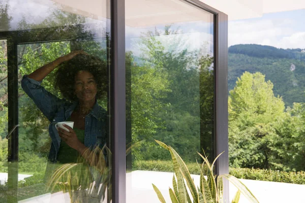 African American Kobieta Picia Kawy Patrząc Przez Okno — Zdjęcie stockowe