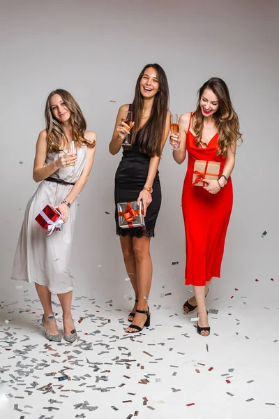 美しいドレスの3人の陽気な友人はワインのメガネで新年を祝います — ストック写真
