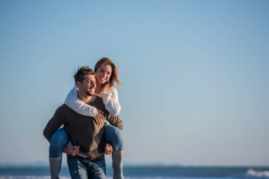 Çiftler sonbaharda kumsalda eğleniyorlar.