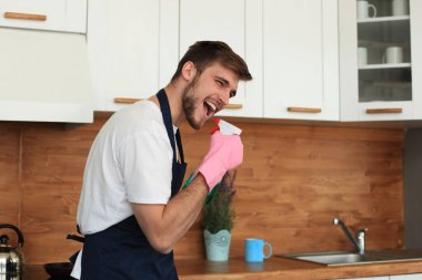 Genç adam modern mutfağını temizlerken eğleniyor..