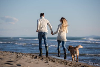 Köpekli çift sonbahar günü sahilde eğleniyor.