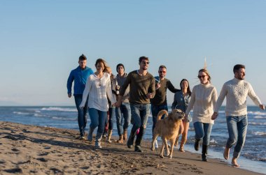 Sonbahar günü plajda koşan bir grup arkadaş