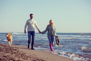 Köpekli çift, sonbahar günü sahilde eğleniyor.