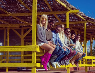 Bir grup arkadaş, sonbahar günü kumsalda eğleniyorlar.