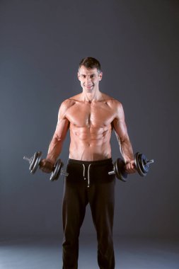 Yakışıklı kaslı adam dumbell ile çalışma dışarı. Kişisel fitness eğitmeni. Kişisel eğitim.
