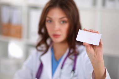 Güzel, genç, gülümseyen bayan doktor masada oturuyor ve yazıyor..