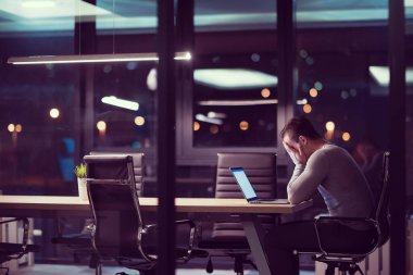 karanlık ofiste dizüstü bilgisayarda çalışan adam