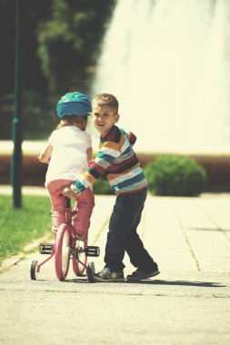 Erkek ve kız parkta Bisiklete binmek için öğrenme