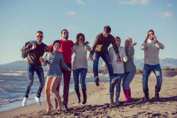 Jóvenes Amigos Saltando Juntos Playa Otoño —  Fotos de Stock