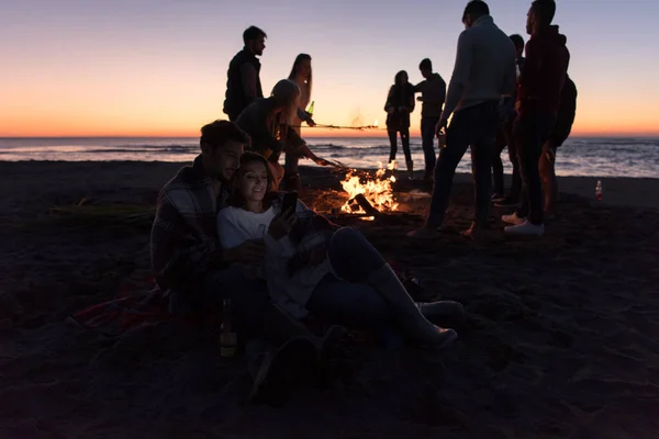 在海滩上和朋友一起享受篝火的夫妻 — 图库照片