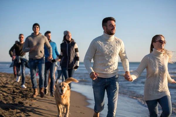 stock image Group of friends running on beach during autumn day