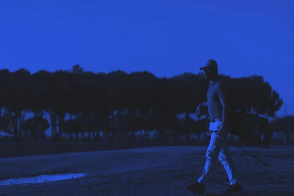 ウォーキングや美しい夕日でゴルフバッグを運ぶゴルファー — ストック写真