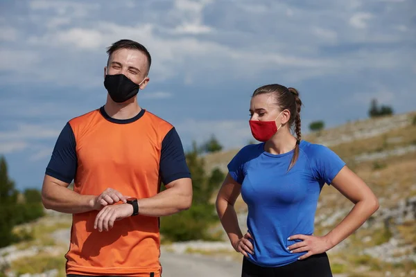 couple of running in nature wearing mask having a break