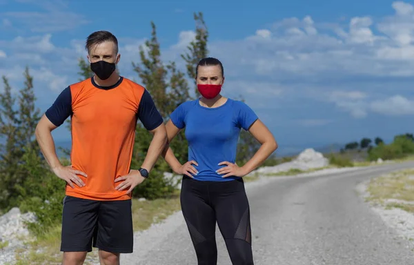 couple of running in nature wearing mask having a break