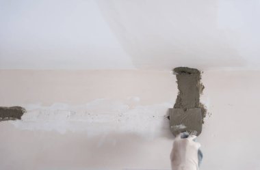Alçıtaşı duvarlara sıva yapan inşaat işçisi.