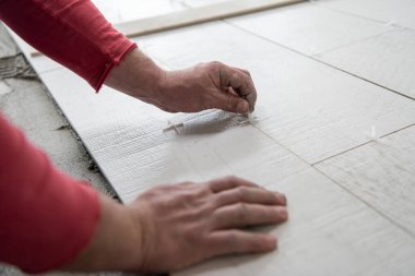 İşçi seramik ahşap efektlerini yere yerleştiriyor.