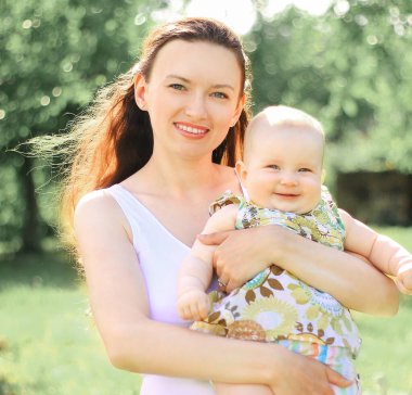 mutlu anne küçük bir kızı onun kollarında tutar.