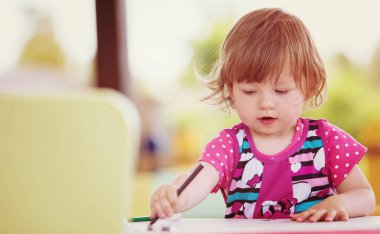 Küçük kız renkli resimler çiziyor.