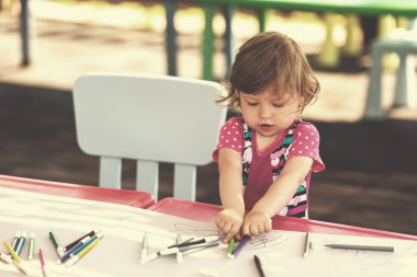 Küçük kız renkli resimler çiziyor.