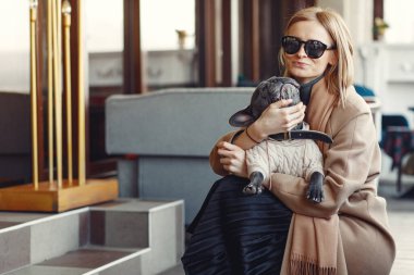 Kahverengi ceketli, siyah bulldog giyen zarif bir kadın.