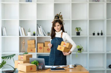 Evden çalışıyorum. Çevrimiçi ürün satan mutlu kadınlar, fiyatları hesaplamak ve posta ücretine hazırlanmak için dizüstü bilgisayar kullanarak küçük bir işletme sahibi kurarlar.