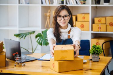 İşyeri sahibi paket kutuları alıyor ve çevrimiçi siparişleri kontrol etmek için bir bilgisayar kullanıyor. Müşterilere gönderilecek ürünleri paketle