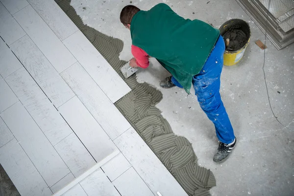 床にセラミックの木効果タイルを設置する作業員は — ストック写真
