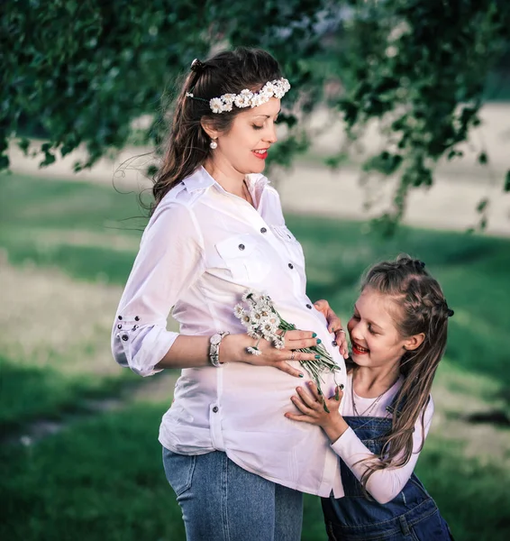 夏の日に散歩のために彼女の小さな娘と幸せな妊娠中のお母さん — ストック写真