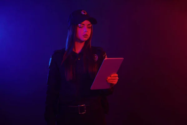 Serieuze Vrouwelijke Politieagent Poseren Voor Camera Tegen Een Zwarte Achtergrond — Stockfoto