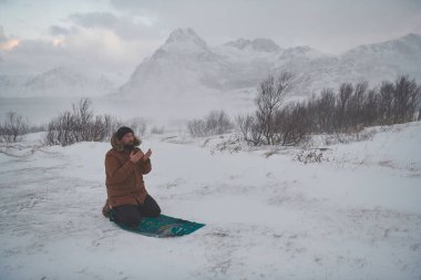 Müslüman gezgin soğuk kış gününde dua ediyor.