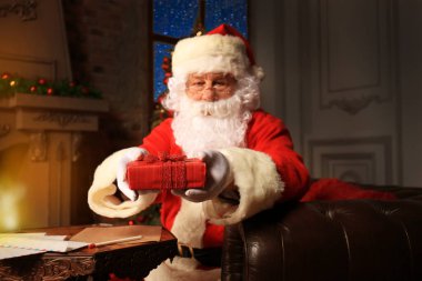 Mutlu Noel Baba 'nın portresi Noel ağacının yanındaki odasında oturuyor ve Noel mektubu ya da dilek listesi okuyor..