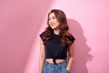 güzel portre Asya neşeli genç kız pembe arka plan üzerinde izole duran gülümseyerek rahat giysiler içinde poz