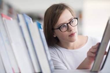 kitaplıkta okumak için kitap seçme kız öğrencinin portresi