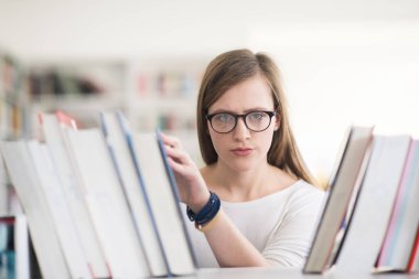 kitaplıkta okumak için kitap seçme kız öğrencinin portresi
