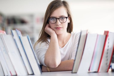kitaplıkta okumak için kitap seçme kız öğrencinin portresi
