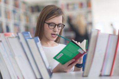 kitaplıkta okumak için kitap seçme kız öğrencinin portresi