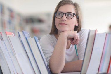 kitaplıkta okumak için kitap seçme kız öğrencinin portresi