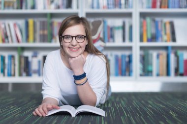 kız öğrenci kütüphanede çalışıyor, tablet kullanıyor ve internetten bilgi arıyor