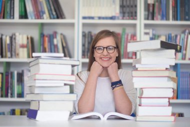 kız öğrenci kütüphanede çalışıyor, tablet kullanıyor ve internetten bilgi arıyor