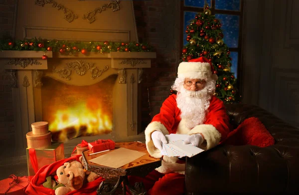 サンタ クリスマスの手紙をクリスマス ツリーに座って 押しながら暖炉のそばで一休み — ストック写真