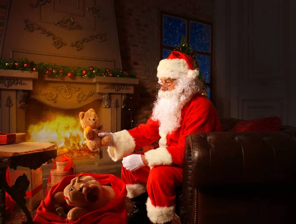 圣诞老人坐在他家靠近圣诞树的房间里看圣诞信或圣诞祝福清单的画像 — 图库照片