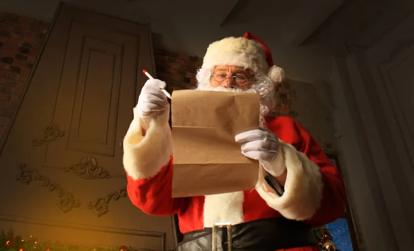 サンタ クロース クリスマス ツリーと大きな袋の近くに自宅に彼の部屋に立っていると クリスマスの手紙を読み書きしてウィッシュ リスト — ストック写真